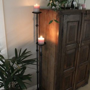 Candle stands with lit candles on them next to cabinet