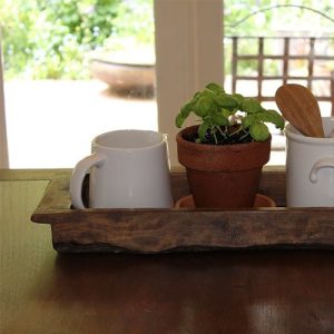 Mango Wooden Tray, sitting on a dining table with a view of the garden in the background.
