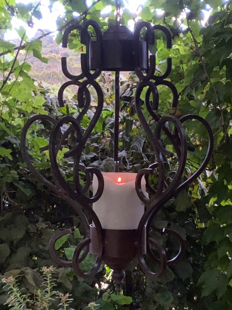 Iron chandelier with candle hanging in a garden