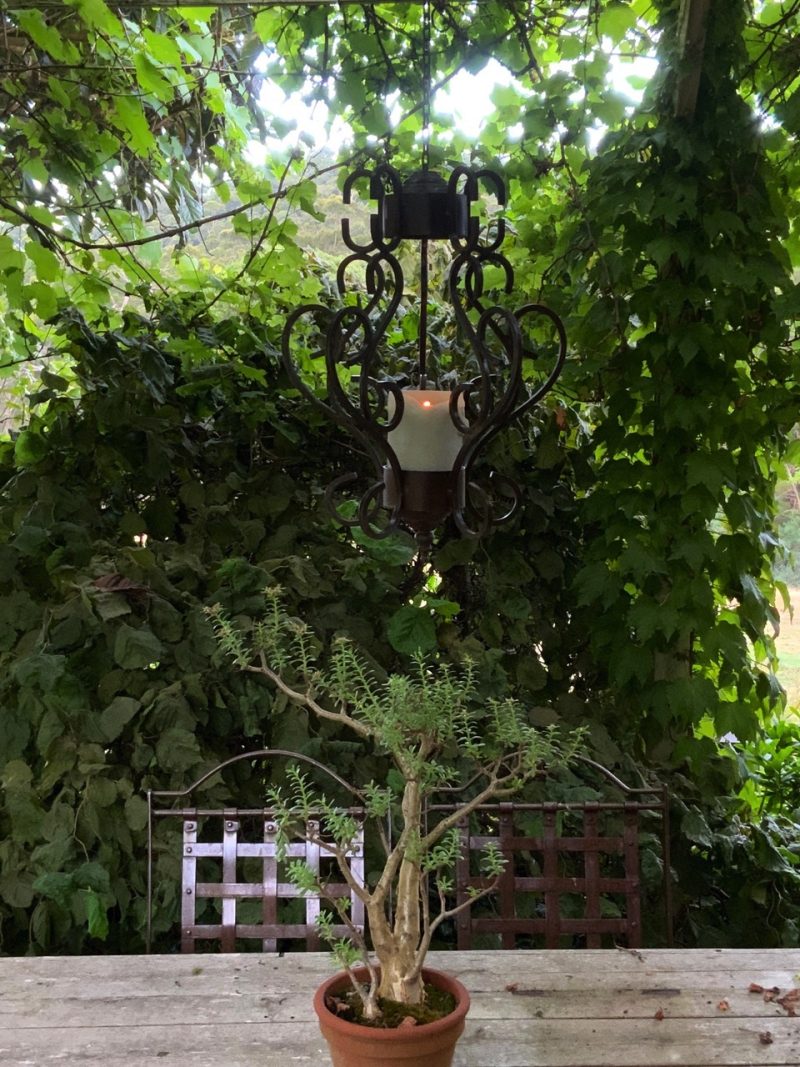 Iron chandelier hanging over a table in a garden