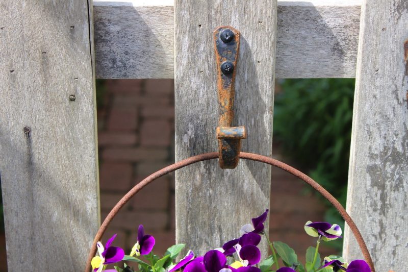 pansies in a planter hanging from iron hook