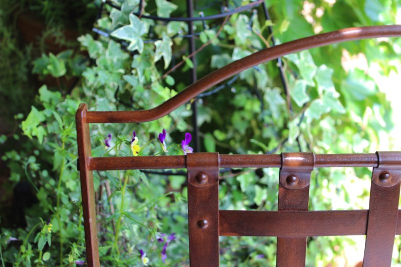 iron chair in a garden with pansies