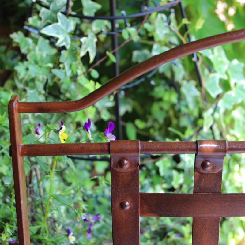 iron chair in a garden with pansies